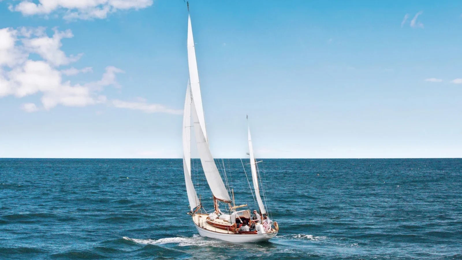A sailboat out on the open sea under a wide blue sky