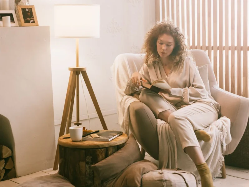 Woman reading in an armchair under a warm lamp