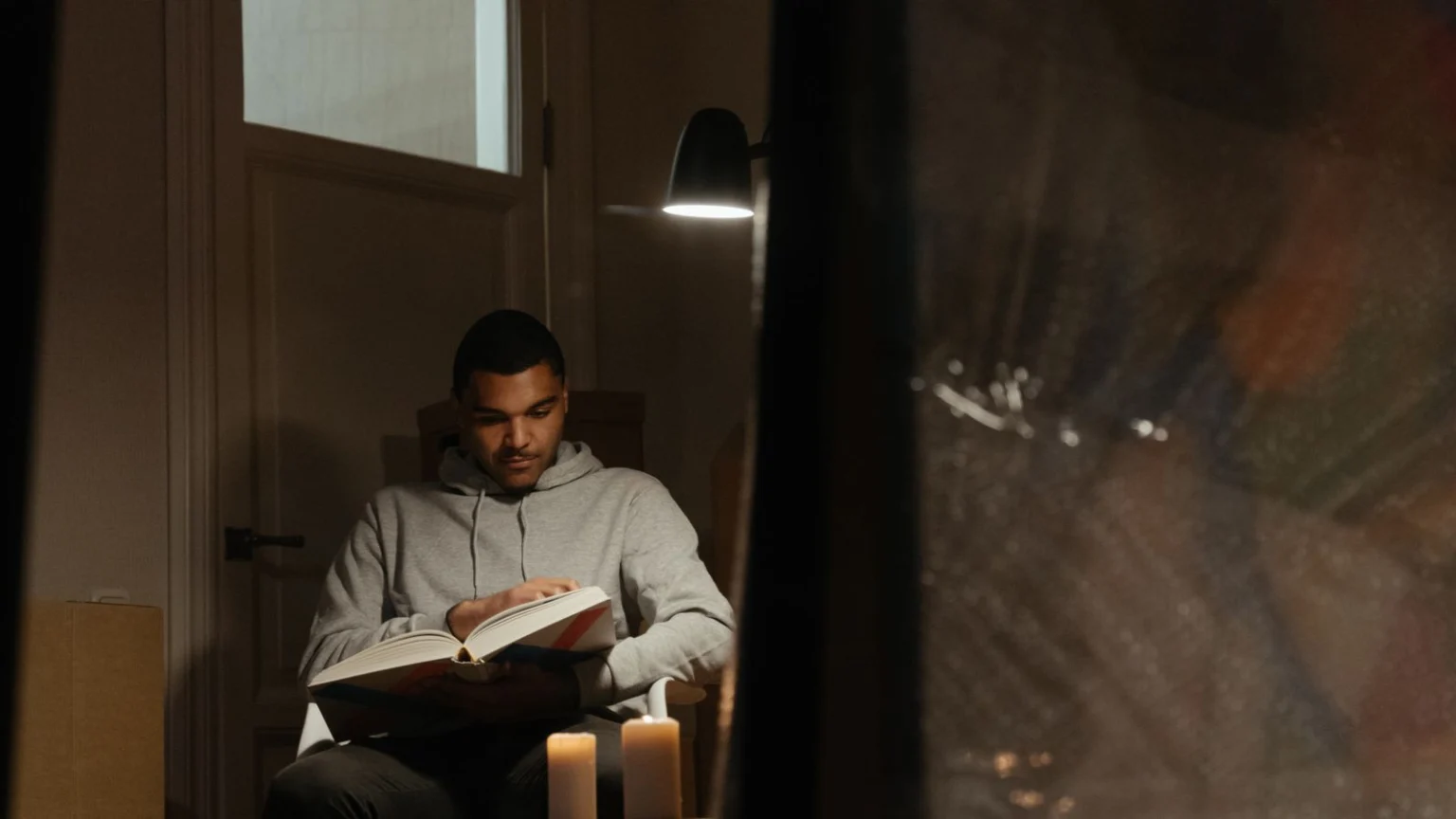 Man reading a book at home by lamplight