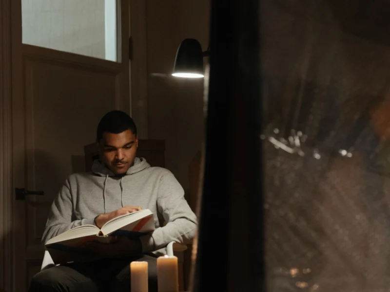 Man reading a book at home by lamplight