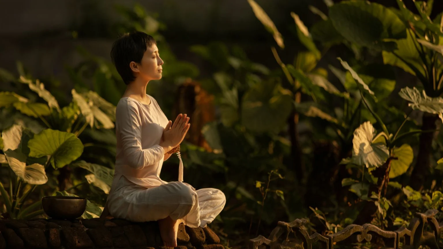 Woman meditating among garden plants