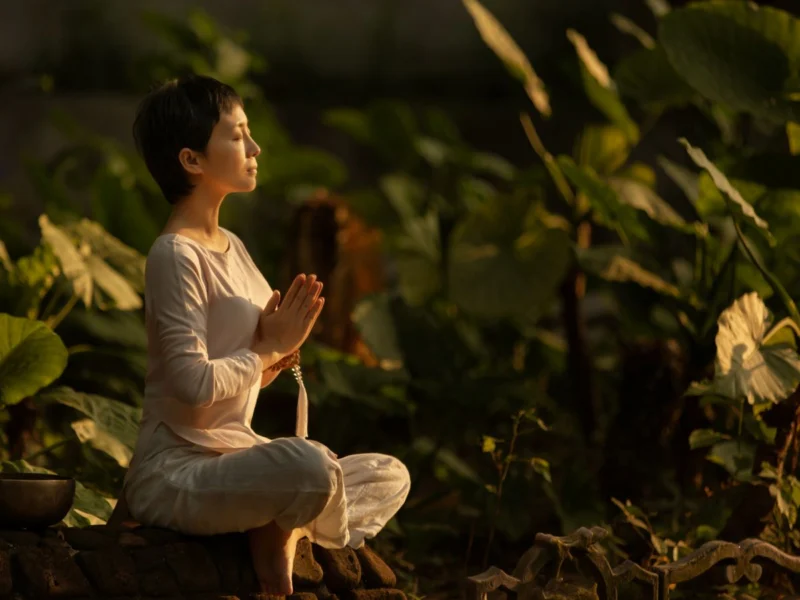 Woman meditating among garden plants