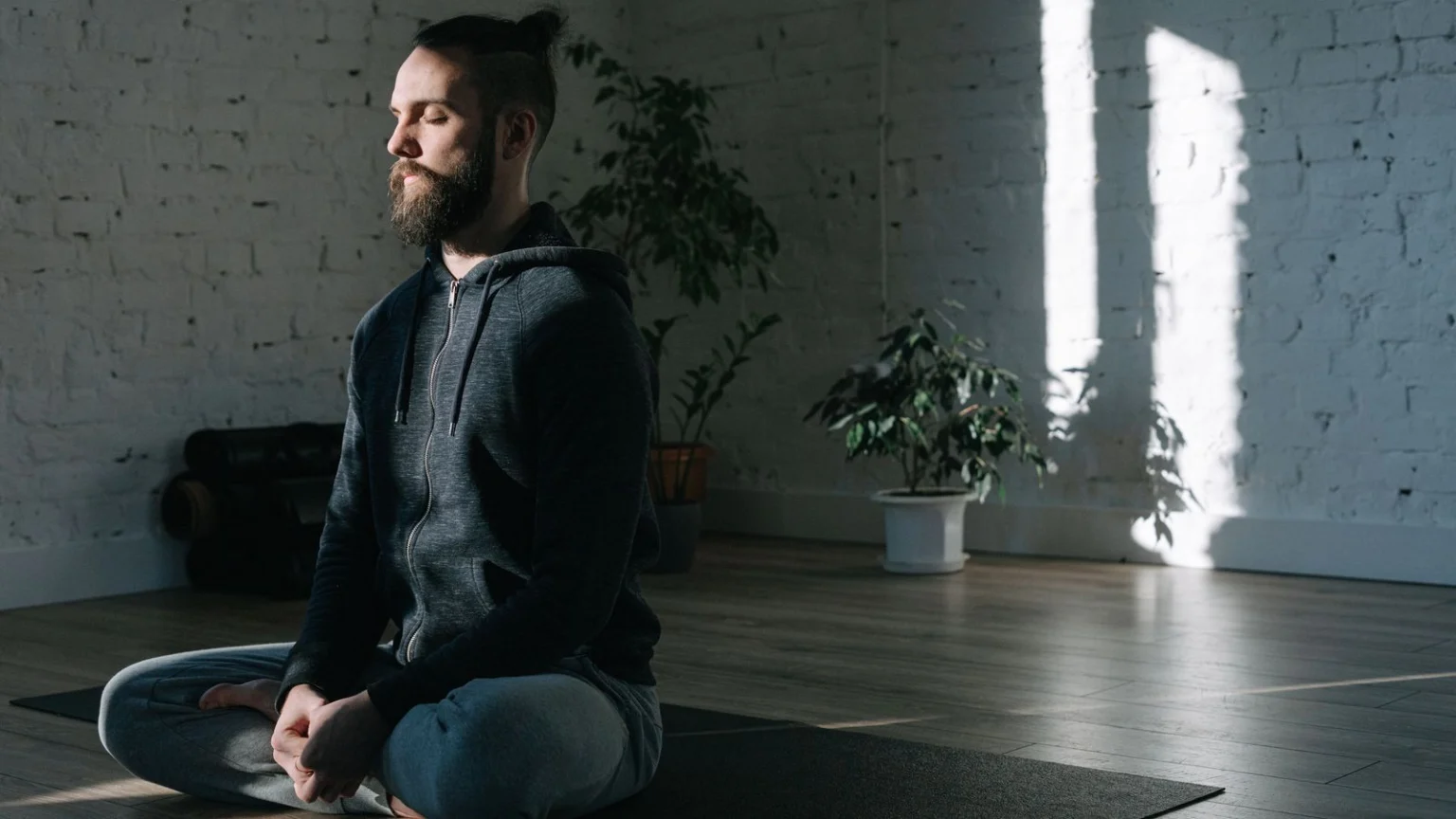 Man meditating on a yoga mat in a bright room