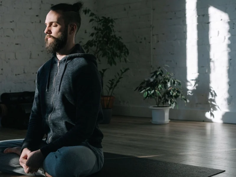 Man meditating on a yoga mat in a bright room