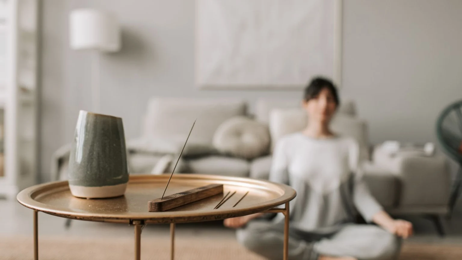 Woman meditating at home beside a table with incense
