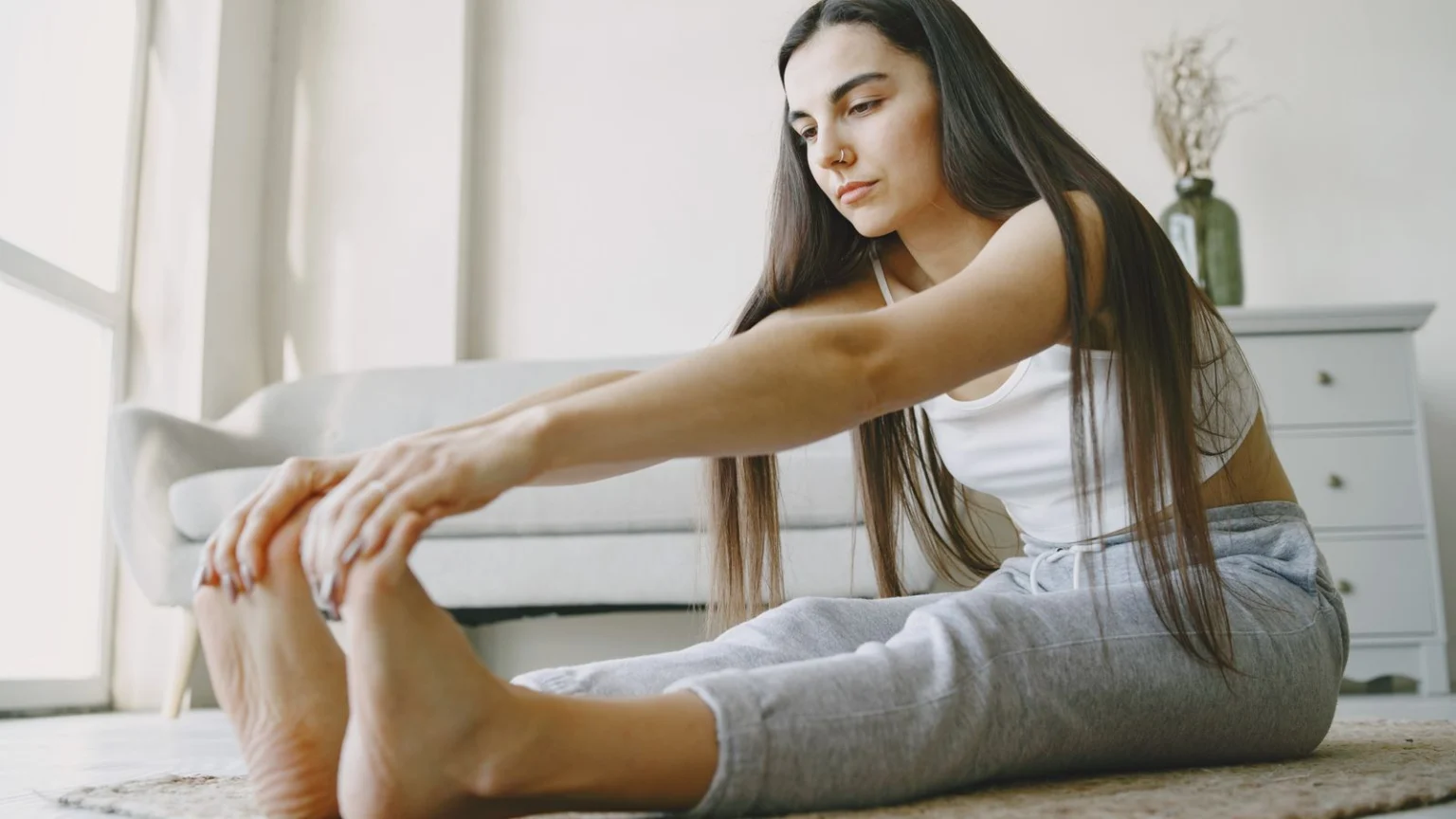 Woman doing a seated forward stretch at home