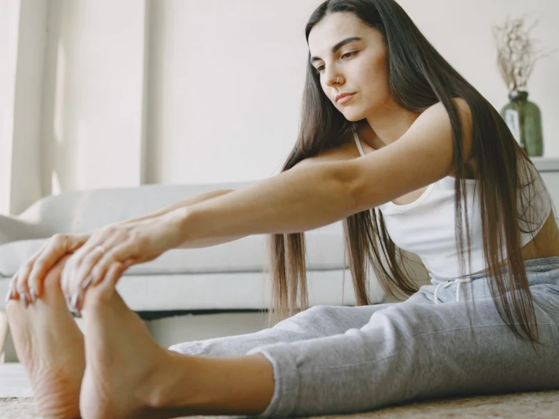 Woman doing a seated forward stretch at home