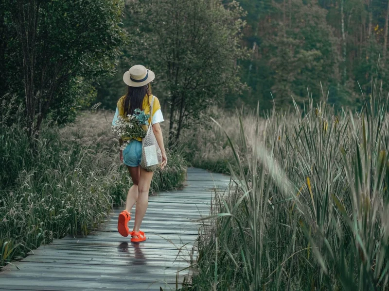 Woman in a sun hat walking along a wooden boardwalk