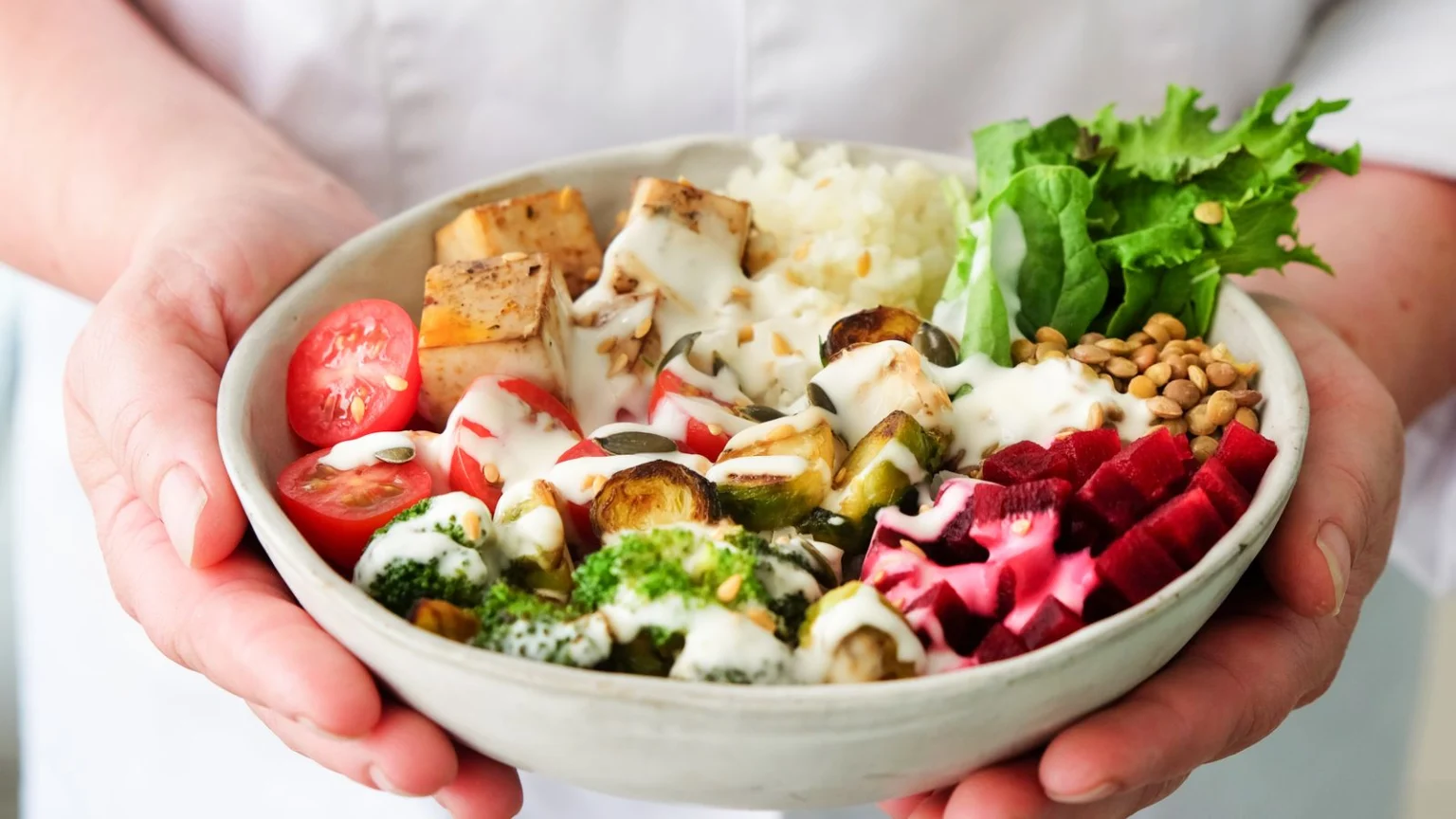Hands holding a colourful vegetable salad bowl