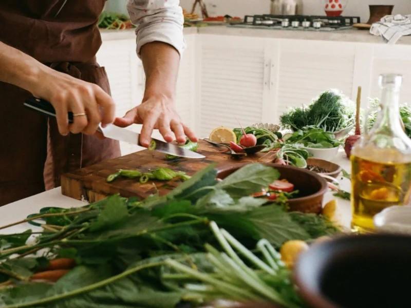 Person preparing a fresh vegetable salad in a home kitchen